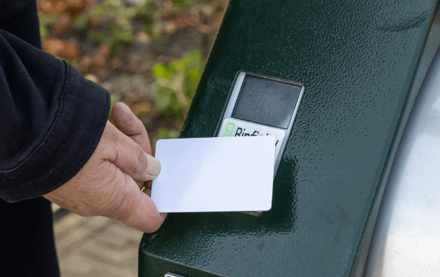 Toegang met pas bij Binfinity Access Close-up van hand met witte pas bij groene lezer van de container (Binfinity Access)