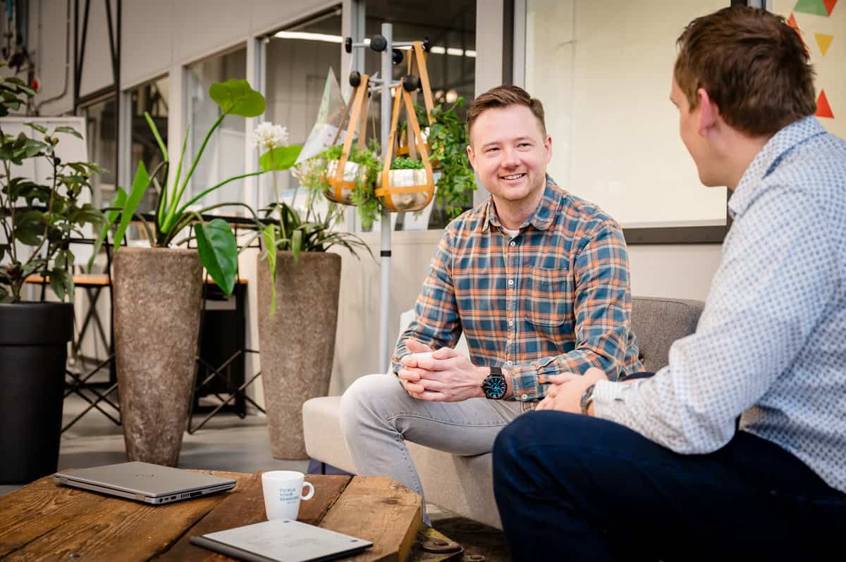 Samenwerking bij Binfinity Teamlid van Binfinity in gesprek met collega in een moderne kantooromgeving